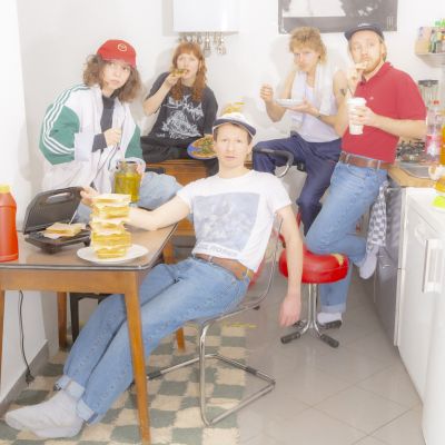 Bandphoto of Potato Beach. 5 bandmembers sitting in the kitchen.